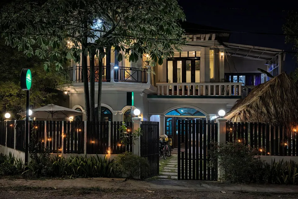 The guesthouse at night, lanterns glowing along the fence and the garden gate open